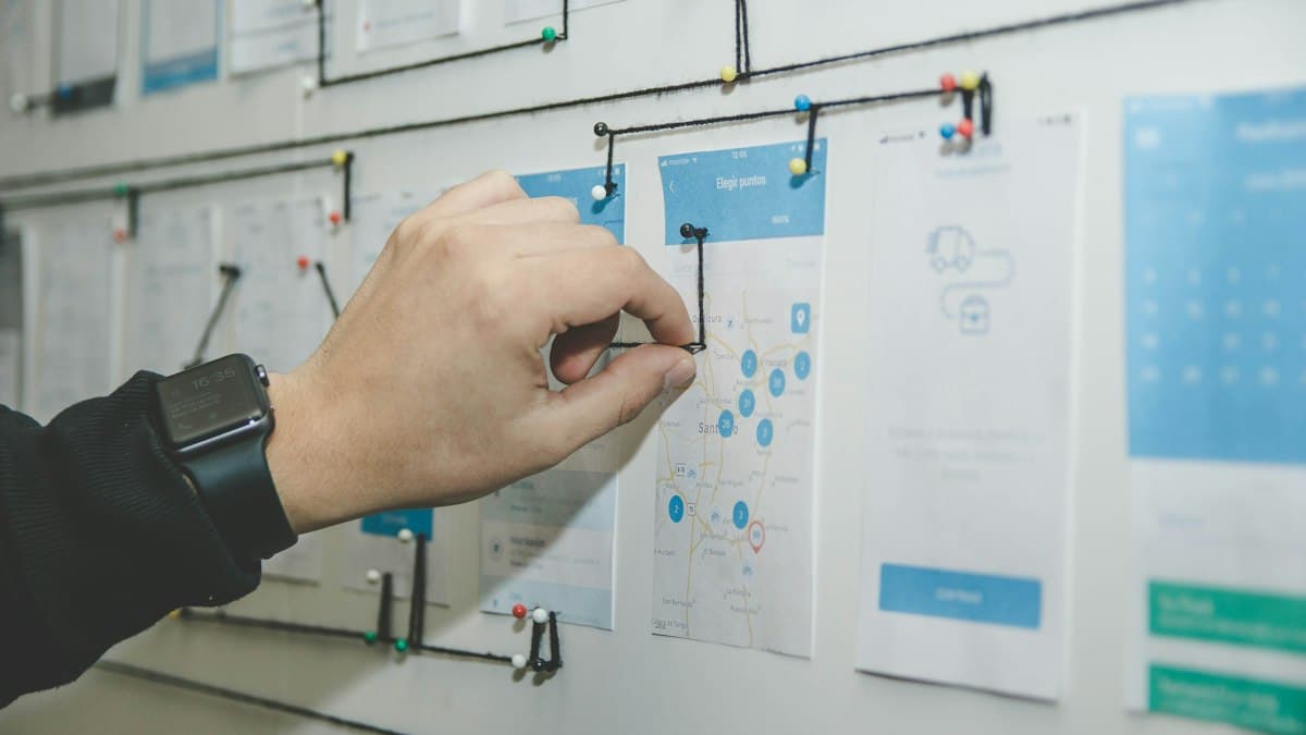 A hand adjusting a step on a process map of connected cards pinned to a wall